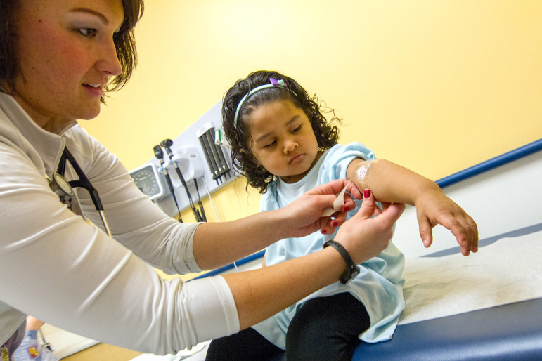 Three-year-old Angely Nunez watches as Lauren Frazer, a nurse at Connecticut Children's Medical Center, applies a topical anesthetic to her arm before a blood draw to check for lead levels.
