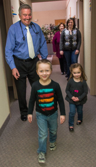 Dr. David R. Howlett follows two of his younger patients, Carter Pochron 4, and sister Haylee, 3, down the hall.  