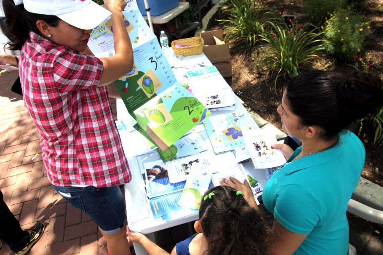 Elizabeth Quinonez shows off early childhood developmental charts with parents at the Danbury Farmers' Market in July. Quinonez, the community coordinator for Danbury's Promise for Children Partnership, has recruited about 20 parents who speak English and Spanish to spread the word about the programs. 